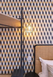 Lampe suspendue sur fond de papier peint géométrique.