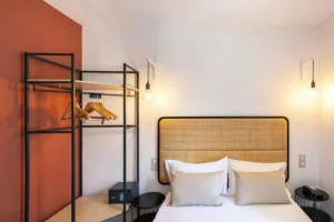 Chambre d'hôtel avec lit double et étagères ouvertes.