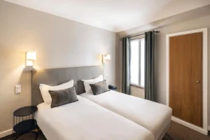 Chambre d'hôtel avec deux lits jumeaux et fenêtre.