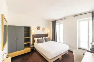 Chambre moderne avec lit double et armoire grise.
