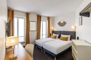 Chambre d'hôtel moderne avec lits jumeaux et bureau.