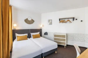 Chambre d'hôtel moderne avec deux lits simples.