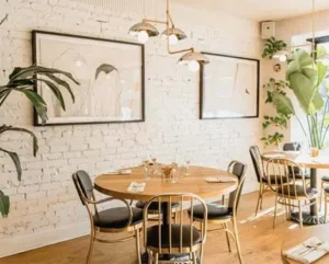 Intérieur de café moderne avec plantes et chaises dorées.